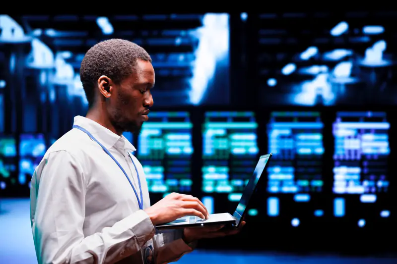 Technicien en salle serveurs, ordinateur portable en main
